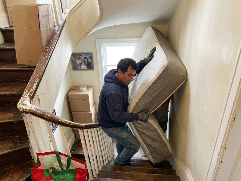 Crew navigating a mattress around a stairwell corner
