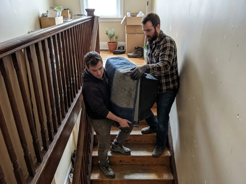 Crew carrying an old CRT television downstairs