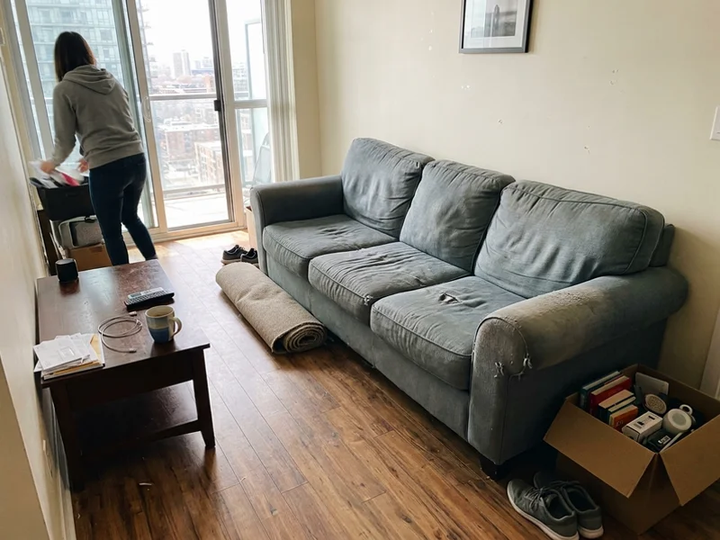 Old worn couch in a condo living room before pickup